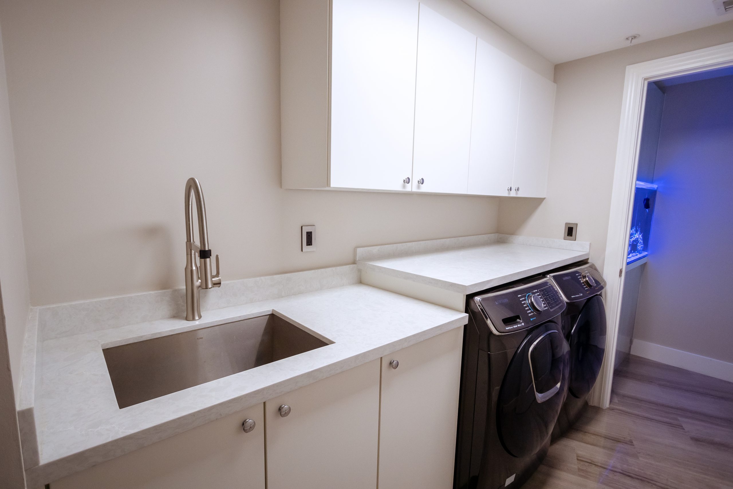 White marble laundry room countertop with washer and dryer, sink