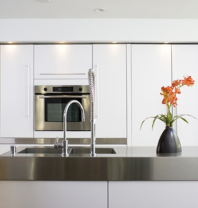 Stove sink and gray marble countertop with red flowers in a modern kitchen.